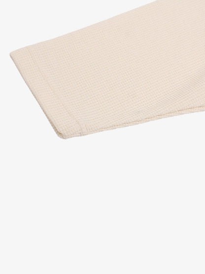 Waffle-knit long-sleeve top displayed flat to show its shape