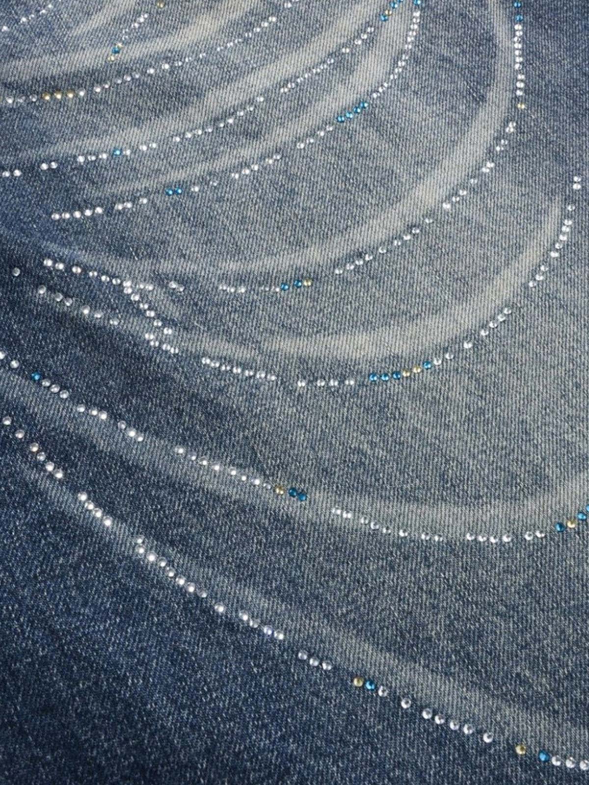 Side view of embellished jeans highlighting the curved-leg cut