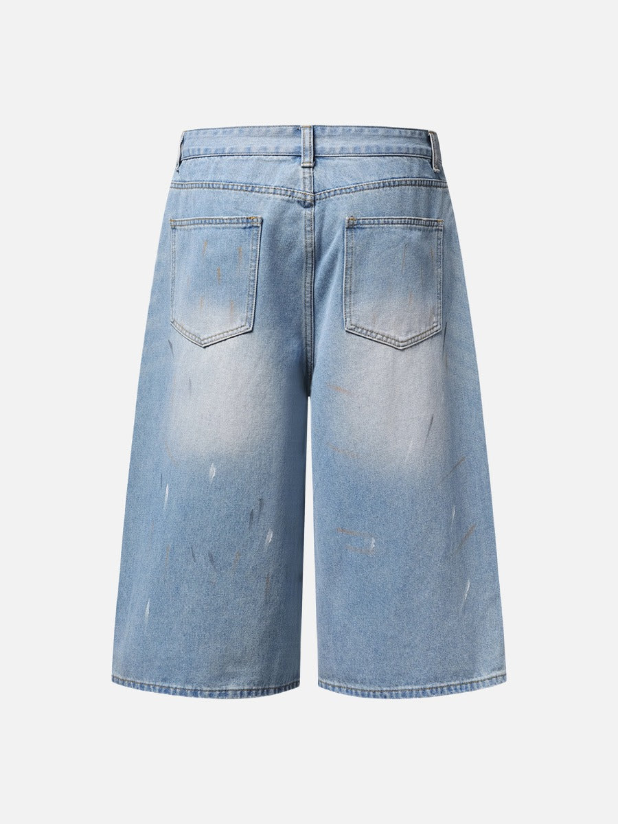 Close-up of paint splatter detail on faded light blue denim shorts