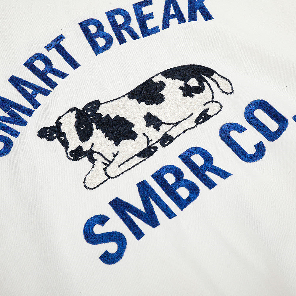White jacket showing its embroidered cow motif in detail
